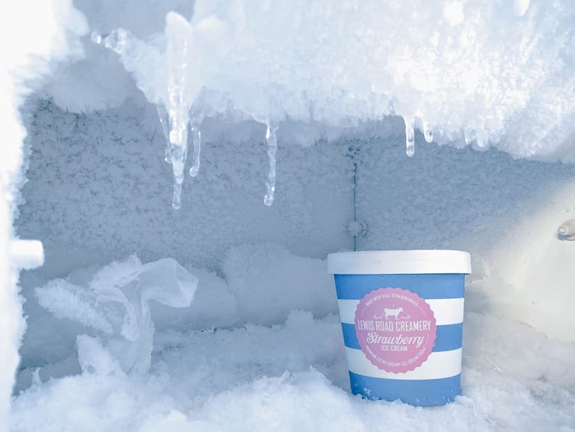 Un congélateur rempli de cristaux de glace avec une barquette de sorbet à l'intérieur