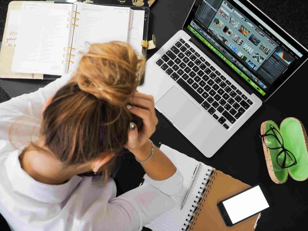 Une femme devant un ordinateur se prenant la tête dans les mains. Elle semble anxieuse et stréssée. Le CBD est connu pour ses actions anxiolytiques améliorant le bien-être