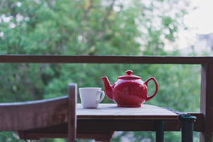 Une theiere rouge accompagnée de sa tasse remplie d'une infusio nde CBD symbolisant la préparation de cette boisson