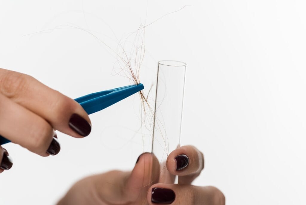 Gros plan sur la prise d'un echantillon de cheveux en laboratoire